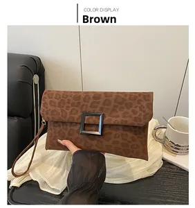 Close-up of brown leopard print envelope clutch bag with matte black square buckle detail