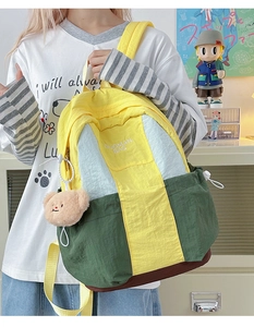 Detail of color-block nylon backpack with plush bear charm and white logo text