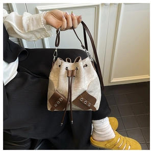 Detail showing the drawstring closure and mixed canvas and leather textures of the bucket bag