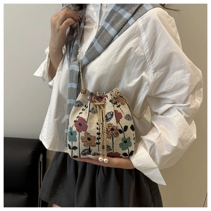 Détail du sac seau floral avec chaîne dorée et cordons élégants ornés de perles