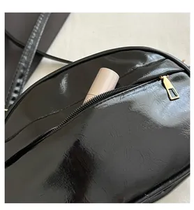 Close-up of black glossy crossbody bag with golden zipper showing interior storage space