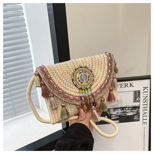 Detail of bohemian straw bag with colorful embroidery, beads and pink tassels