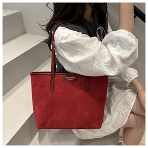 Close-up of red suede tote bag with leather shoulder straps and vintage brand logo