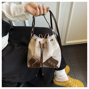 Detail of vintage canvas bucket bag featuring brown leather trim and drawstring closure