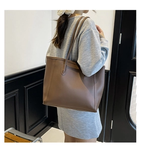 Side view of a vintage brown leather tote bag worn by a model in a minimal room