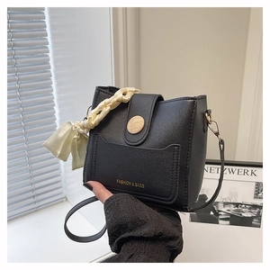 Detail of black lychee grain bucket bag with silk scarf handle and wooden button accent