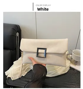 Detail of minimalist white envelope clutch with black square buckle and wrist strap