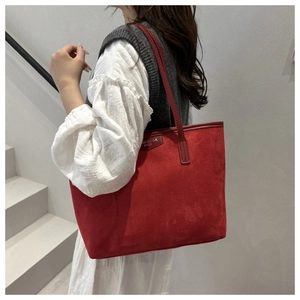 Macro detail of red frosted suede tote bag with Anyissa metallic logo and long strap
