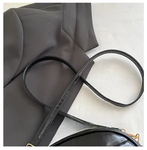 Detail of adjustable glossy black patent leather shoulder strap with soft texture