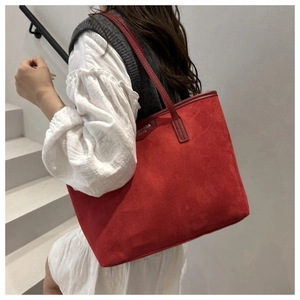 Close-up of red tote bag in matte texture with brand tag on a model at a staircase