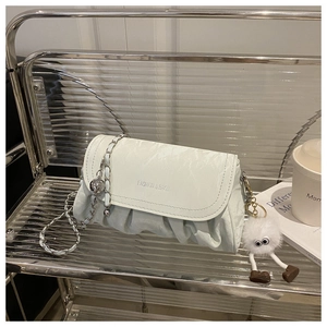 Détail du sac plissé vert menthe avec chaîne argentée et pendentif en peluche