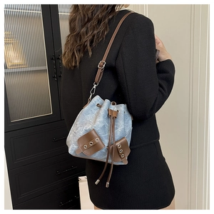 Close-up of vintage blue denim bucket bag with brown leather drawstrings and silver eyelets