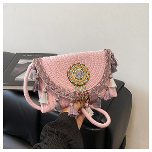 Detail of pink woven bohemian bag featuring ethnic tassels and mandala bead ornament