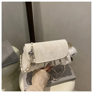 Détail du sac froncé blanc cassé avec chaîne argentée et pendentif monstre en peluche
