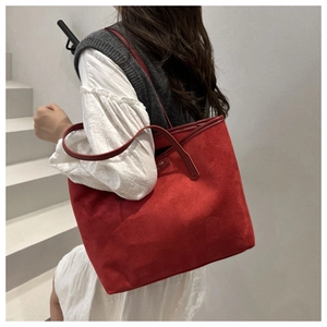 Red suede tote bag on shoulder with minimalist branding and thin straps shown on model