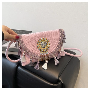 Dettaglio di perle bohémien colorate e nappe su una borsa a tracolla in paglia rosa