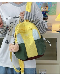 Detailed shot of color-blocked nylon backpack with embroidery and a plush bear charm