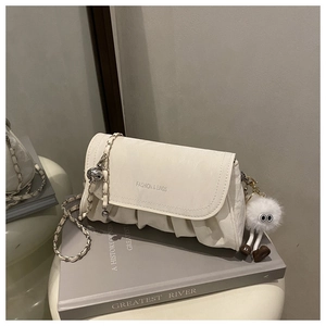 Détail du sac à bandoulière plissé blanc cassé avec chaîne et pendentif monstre peluche