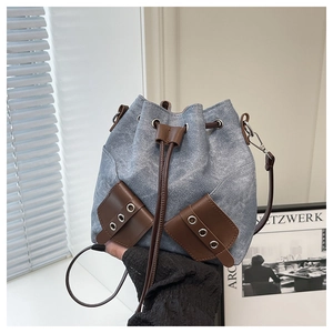 Macro shot of denim bucket bag with brown leather pockets and drawstring closure