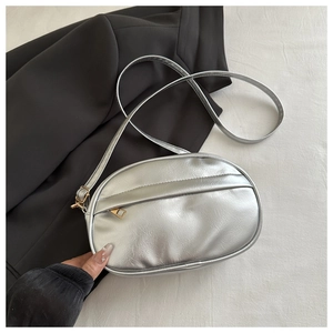 Detail of silver metallic crossbody bag with textured finish on a chic blazer background
