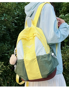 Detail of color-block nylon backpack featuring contrast colors and plush ball charm decoration