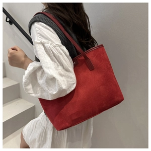 Close-up of red corduroy tote bag featuring soft texture and small side logo detail