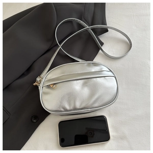 Top view of minimalist silver crossbody bag with golden zipper detail and compact design