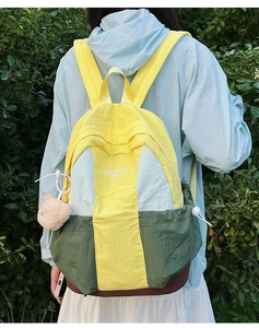 Outdoor shot of a colorful nylon backpack with contrast panels and a cute plush bear charm