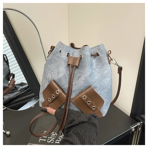 Detail of blue denim bucket bag with brown leather pockets and adjustable shoulder strap