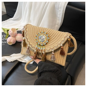 Detail of woven straw bag with colorful tassel charms and ethnic embroidery strap