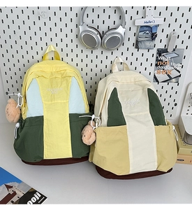 Detail of color-block nylon backpacks with embroidery and cute plush bear charms