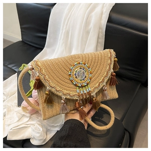 Detail view of woven straw envelope bag with colorful ethnic tassels and beads