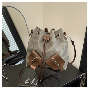 Close-up of vintage canvas bucket bag featuring leather drawstring and metal eyelet details