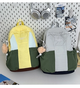 Detail of color-block nylon backpacks featuring embroidered logo and cute plush bear charm