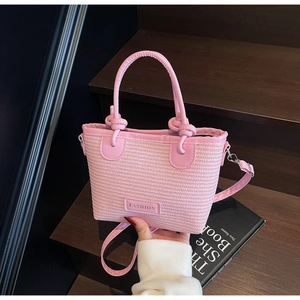 Pink woven tote bag with knotted handle detail and metallic Fashion nameplate