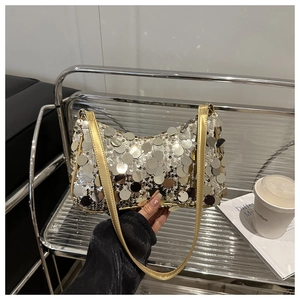 Dettaglio di paillettes d'argento e tracolla in pelle dorata su una borsa chic