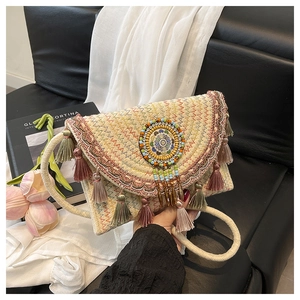 Close-up of bohemian woven straw bag with colorful tassels and embroidery details