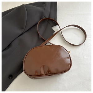 Detail of dark brown semi-circle crossbody bag with smooth leather texture and strap