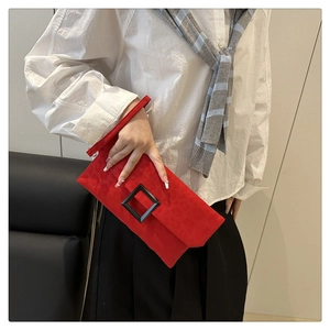 Detail of red suede envelope clutch with subtle leopard embossing and black square buckle