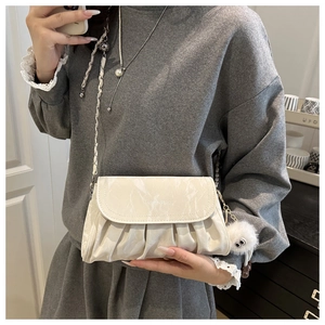 Detailed view of cream-white ruched cloud bag with silver chain and fuzzy charm