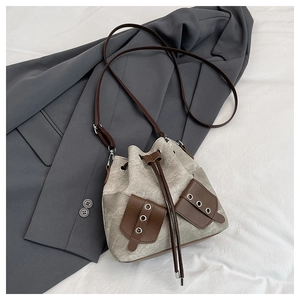 Close-up of canvas bucket bag with leather pockets and drawstring closure detail