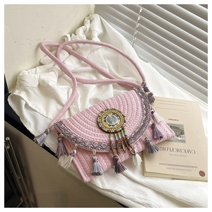 Detailed close-up of pink woven crossbody bag with tassels and ethnic beaded charms