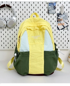 Detail view of the tricolor nylon backpack featuring yellow, blue, and green contrast panels