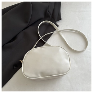 Detail view of the gold-tone zipper and smooth white faux leather texture of the crossbody bag