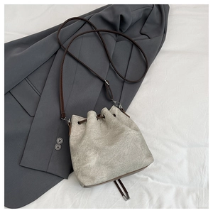 Detail view of canvas bucket bag with leather drawstring and adjustable shoulder strap