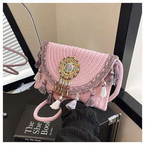 Detail of pink woven straw bag with boho fringes and mandala charm for beach