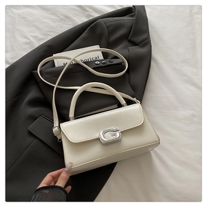 Detailed shot of cream white square handbag with silver crystal G-buckle and textured leather