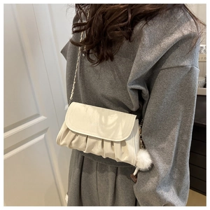 Detail of cream pleated cloud bag with chain strap and soft plush ball pendant