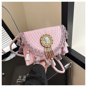 Close-up of pink woven crossbody bag featuring bohemian fringe and beaded badge details