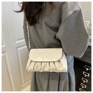 Detail view of a white ruched cloud bag with silver chain strap and logo engraving